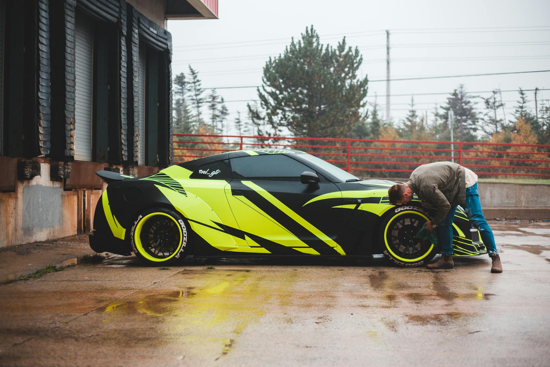 Mężczyzna w casualowym stroju poleruje koło sportowego Porsche