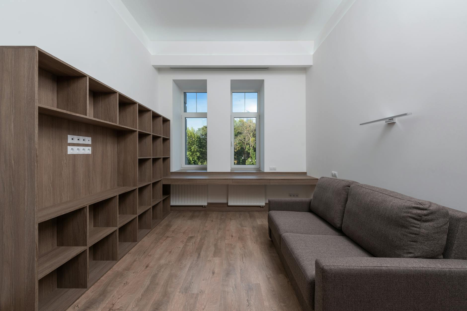 Minimalistyczny salon z zabudową na wymiar i dużymi oknami